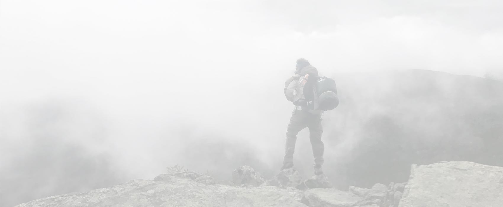 A man in black jacket standing on top of hill.